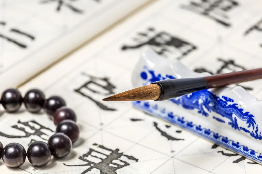 Chinese calligraphy brush resting on rice paper with crystal bracelet, symbolizing Five Elements meaning and traditional energy wisdom.