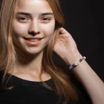 A woman smiling while wearing an aquarius birthstone bracelet for daily mental clarity.