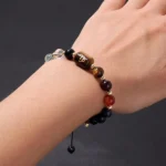 Close-up of a capricorn birthstone bracelet featuring dark Garnet and Tiger's Eye beads on a wrist.