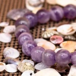 dog teeth amethyst bracelet purple crystal beads close up on shell background