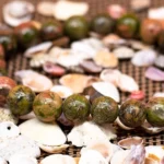 epidote crystal bracelet close up green red bead texture shell background