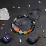 Aries birthstone bracelet surrounded by raw red jasper and carnelian stones on a dark surface.