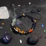 Capricorn birthstone bracelet resting near raw smoky quartz and garnet stones on a dark surface.