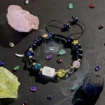Libra birthstone bracelet resting on a dark surface next to raw blue and pink crystal clusters.