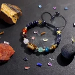 Taurus birthstone bracelet resting near raw rose quartz and green aventurine clusters on a dark surface.