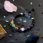 Virgo birthstone bracelet resting near raw amazonite and clear quartz clusters on a dark surface.