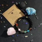 Natural raw stones surrounding a taurus crystal bracelet on a dark textured surface.