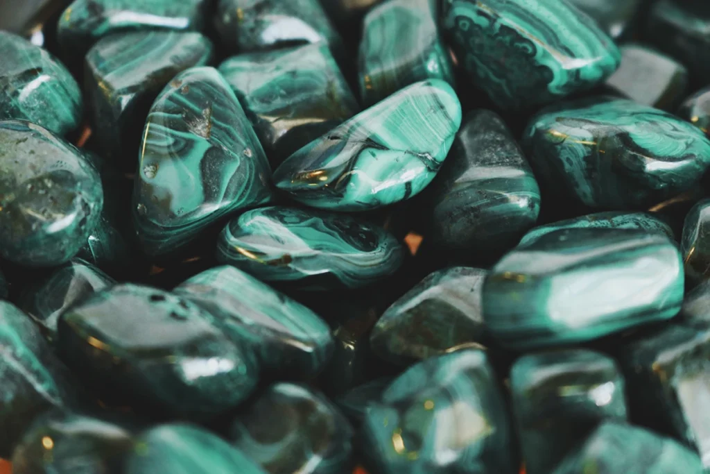 Close-up of polished malachite stones with swirling dark and light green bands at a jewelry display.